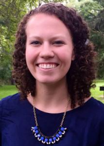 Headshot of Allison Gray with brown curly hair and dark blue blouse.