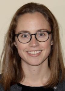 Headshot of Mimi Brinberg with long brown hair, glasses, black top, and gray sweater.