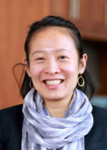 Headshot of Sy-Miin Chow with long black hair, black blouse, purple scarf, and gold hoop earrings.